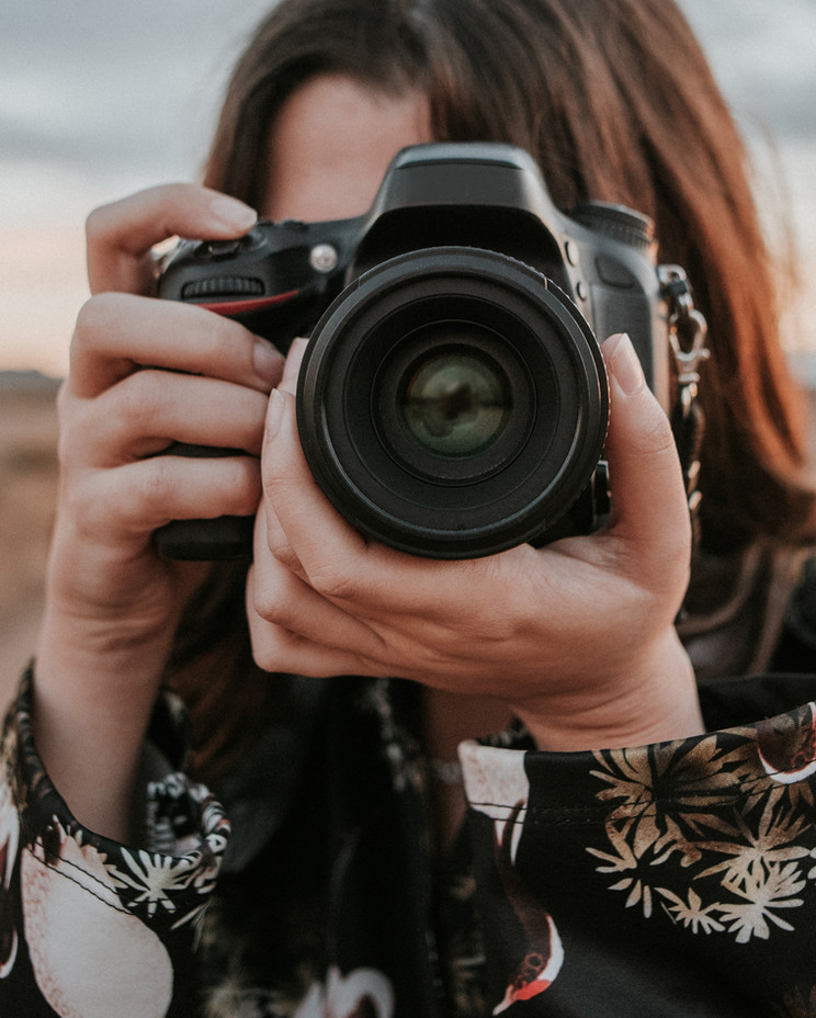 A photographer raising a DSLR camera to frame a shot